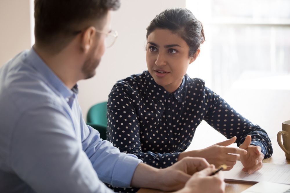 Two people sat at a desk, discussing documents